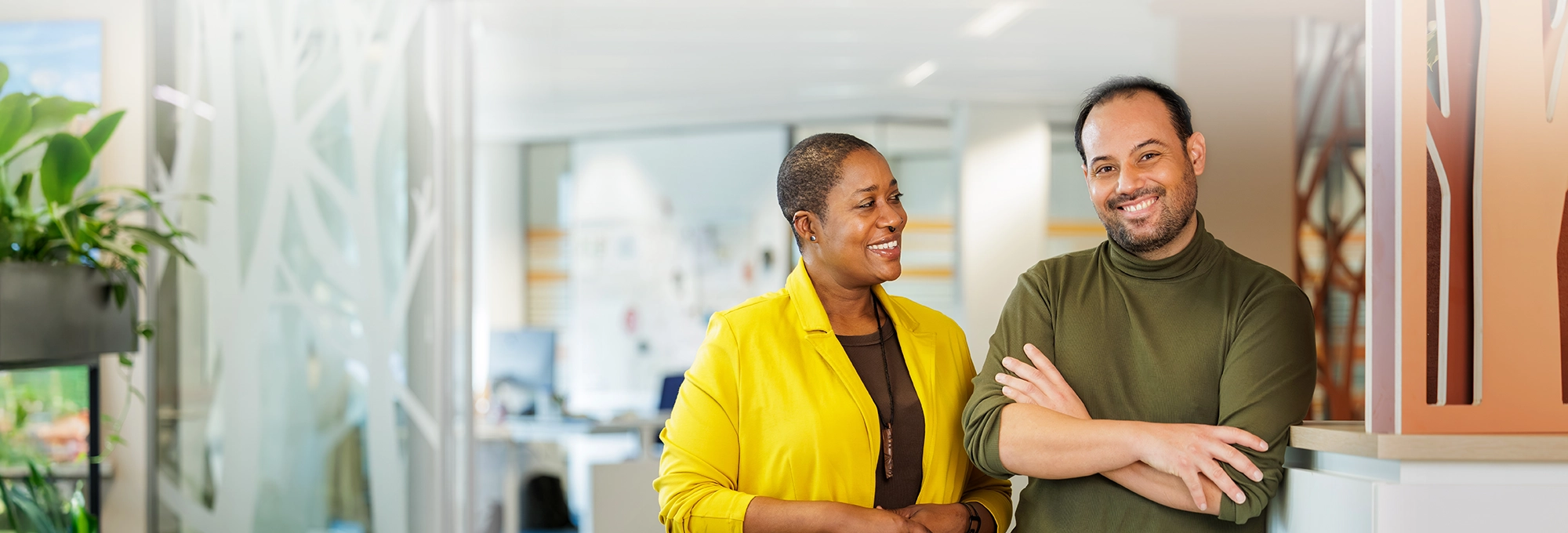 Decoratieve foto van een mannelijke en vrouwelijke collega van de Regionale Belasting groep, welke direct in de camera kijken.